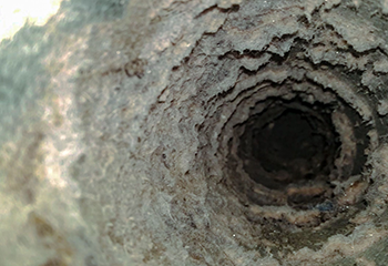 Technician detaching a dryer vent from the wall during a professional cleaning service in Pasadena TX.